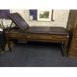 A leather upholstered examination couch with drawers to side.