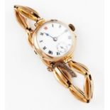 A ladies 9ct yellow gold cased wrist watch, the white enamel dial having hourly Roman numeral