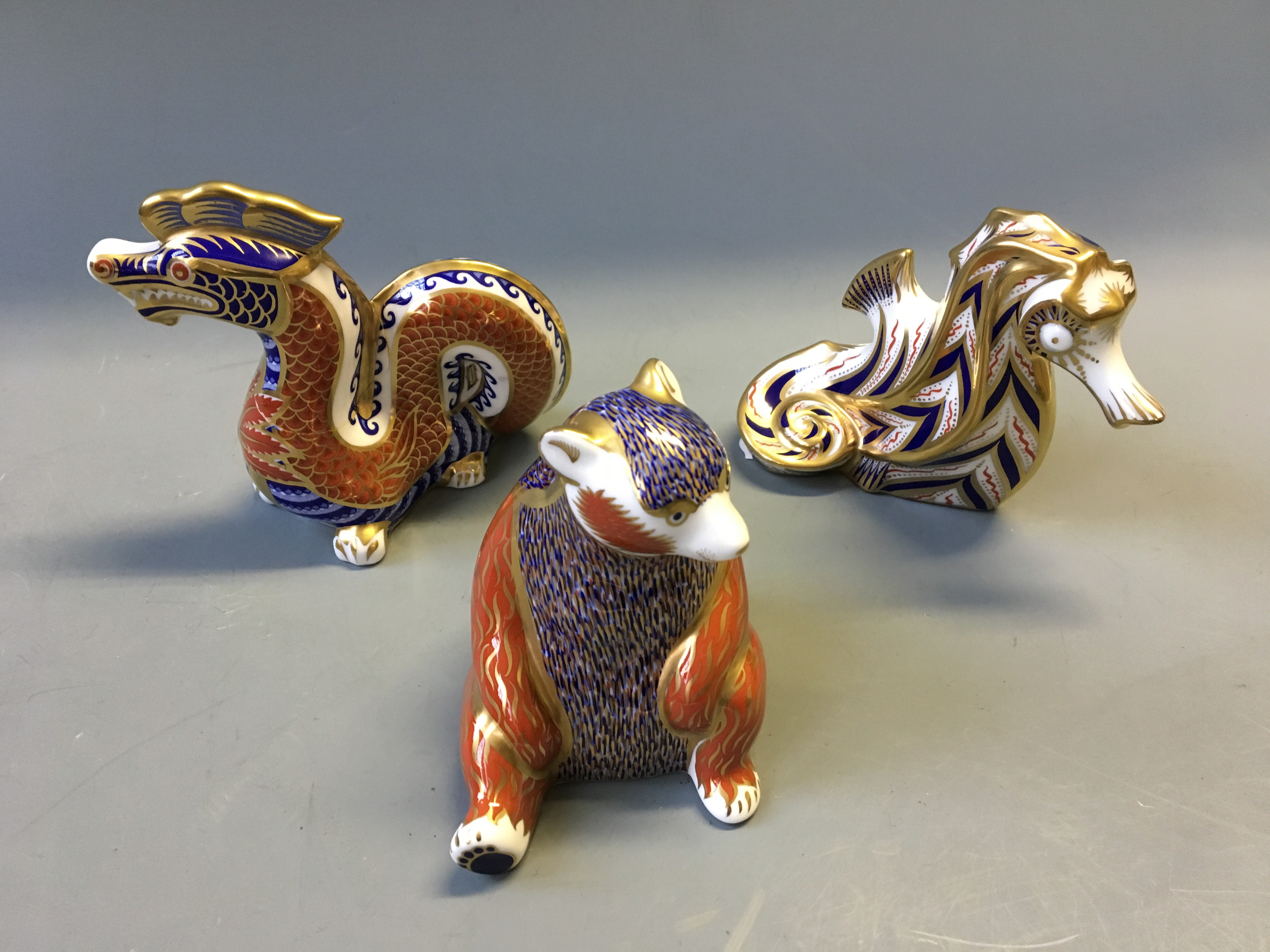 Three Royal Crown Derby figurines, dragon, bear and seahorse.