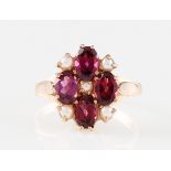 *A 9ct rose gold rhodolite garnet and seed pearl ring, set with four oval cut rhodolite garnets