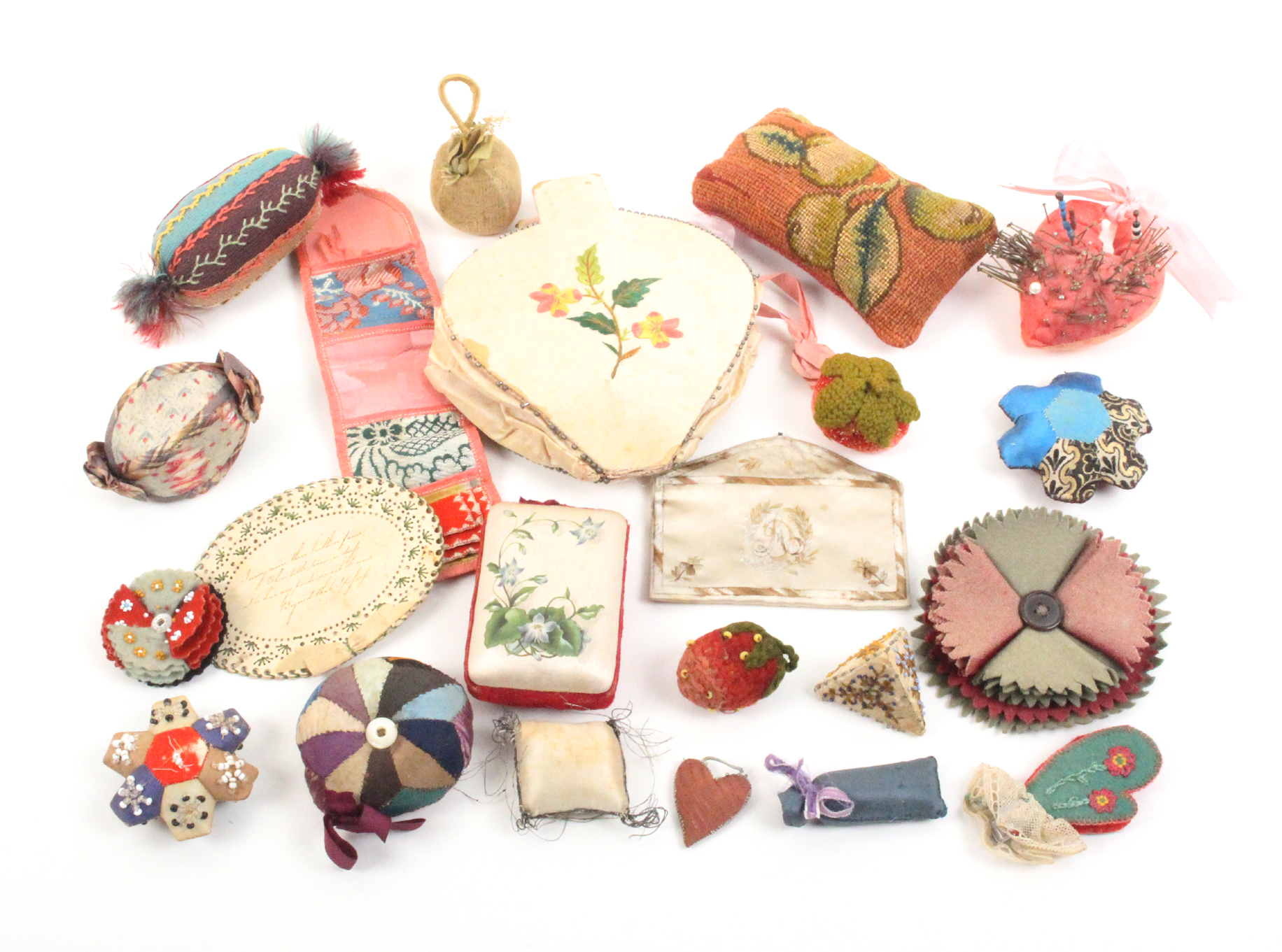 A collection of pincushions including home made examples, an embroidered silk ïSouvenirÍ envelope, a