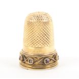 A late 19th/early 20th Century gold thimble the frieze with a plain band over a further wirework