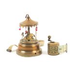 Two metal tape measures comprising a brass example in the form of a fairground carousel, printed