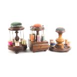 Three wooden reel stands comprising a turned mahogany example incorporating a thimble stand below