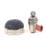 A silver tape measure and pincushion, the tape measure of tapering cylinder form, ball winding