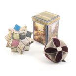 A falling side needlepacket box and two pin stuck large format pincushions the first decorated