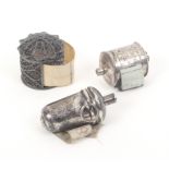Three silver tape measures comprising a cylinder filigree example below a dome top, replacement