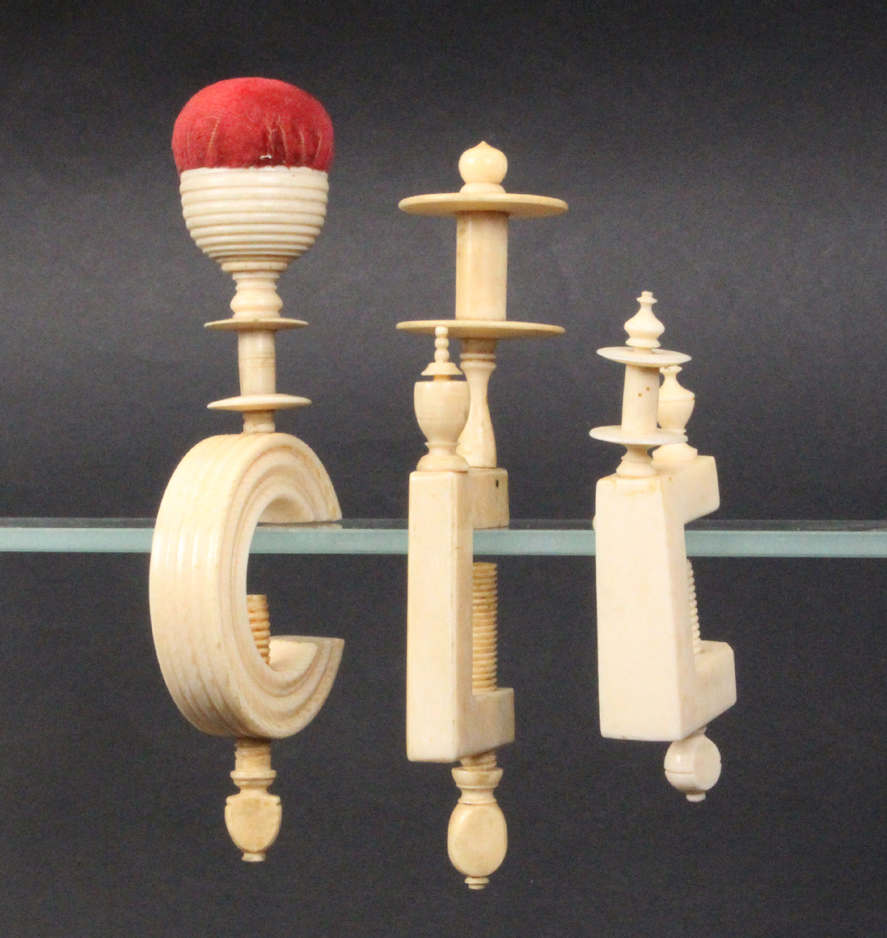 Three 19th Century ivory sewing clamps comprising a turned ïCÍ frame example below a reel and cup