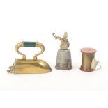 Three metal novelty tape measures comprising a brass iron, 6cm, a gilt brass thimble surmounted by