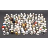 A collection of modern thimbles, glass, ceramic, wooden and metal including two silver examples (