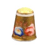 An English porcelain thimble, circa 1820, brightly painted with varient flower heads on a gold