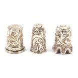 Three Indian Kutch silver thimbles, the first with deep leaf scrolls below a flower top,