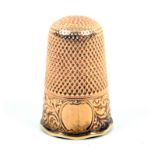 A 19th Century gold thimble of tall form, the leaf scroll frieze with vacant cartouche over an