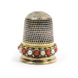 A 19th Century gold thimble, the frieze with a band of alternate coral and pearl coloured stones