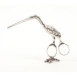 A pair of English silver ribbon scissors as a stork with baby, one oval loop resting on a claw base,
