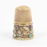 An attractive three colour gold 19th Century thimble, the frosted frieze set with various coloured