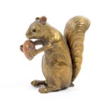 A gilt brass novelty tape measure in the form of a seated squirrel, an acorn between its paws, the