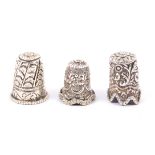 Three Indian Kutch silver thimbles, the first with flower head top over flowering leaf scrolls