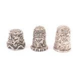 Three Indian Kutch silver thimbles, the first with flower head top over flowers and leaf scrolls,