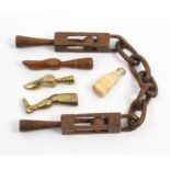 Five 19th Century pipe tampers comprising a late 18th Century wooden example with five link chain