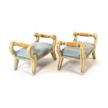 A pair of 19th century Regency style gilt and cream painted sabre leg footstools, with turned and