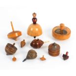 Ten spinning tops and a totem, comprising a boxwood spinning top, 6cm dia, a coquilla nut example,