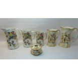 A pair of Crown Ducal graduated Jugs decorated with birds and flowers on a blush ivory ground,