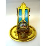 A 19th Century Table Thermometer in gilt brass frame and stand, inset with a painted porcelain panel