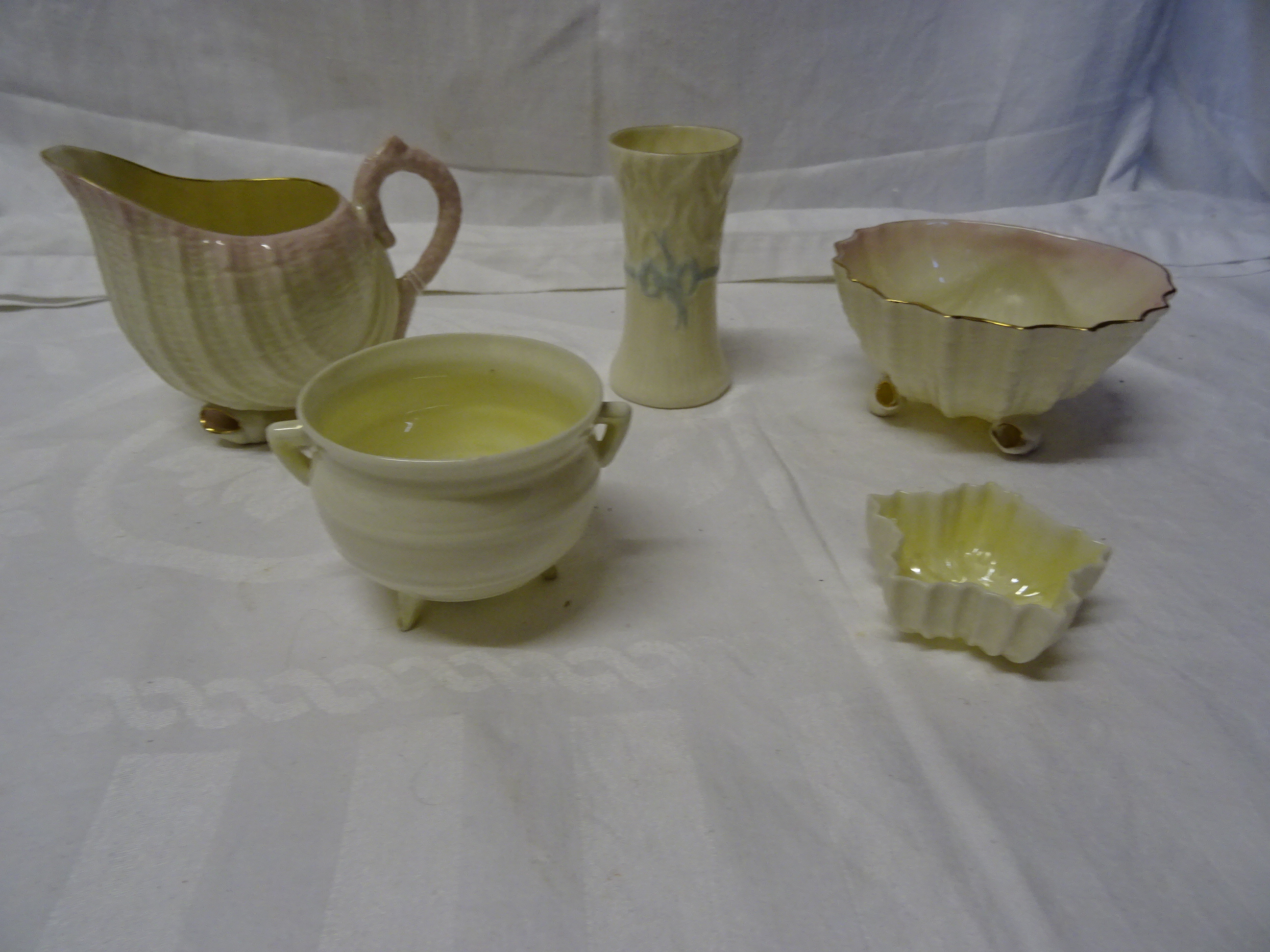A Belleek shell shape Jug on shell feet, similar bowl and three other pieces of Belleek.