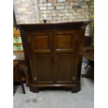 An early 19th Century oak corner Cupboard with stepped cornice enclosed by a pair of fielded panel