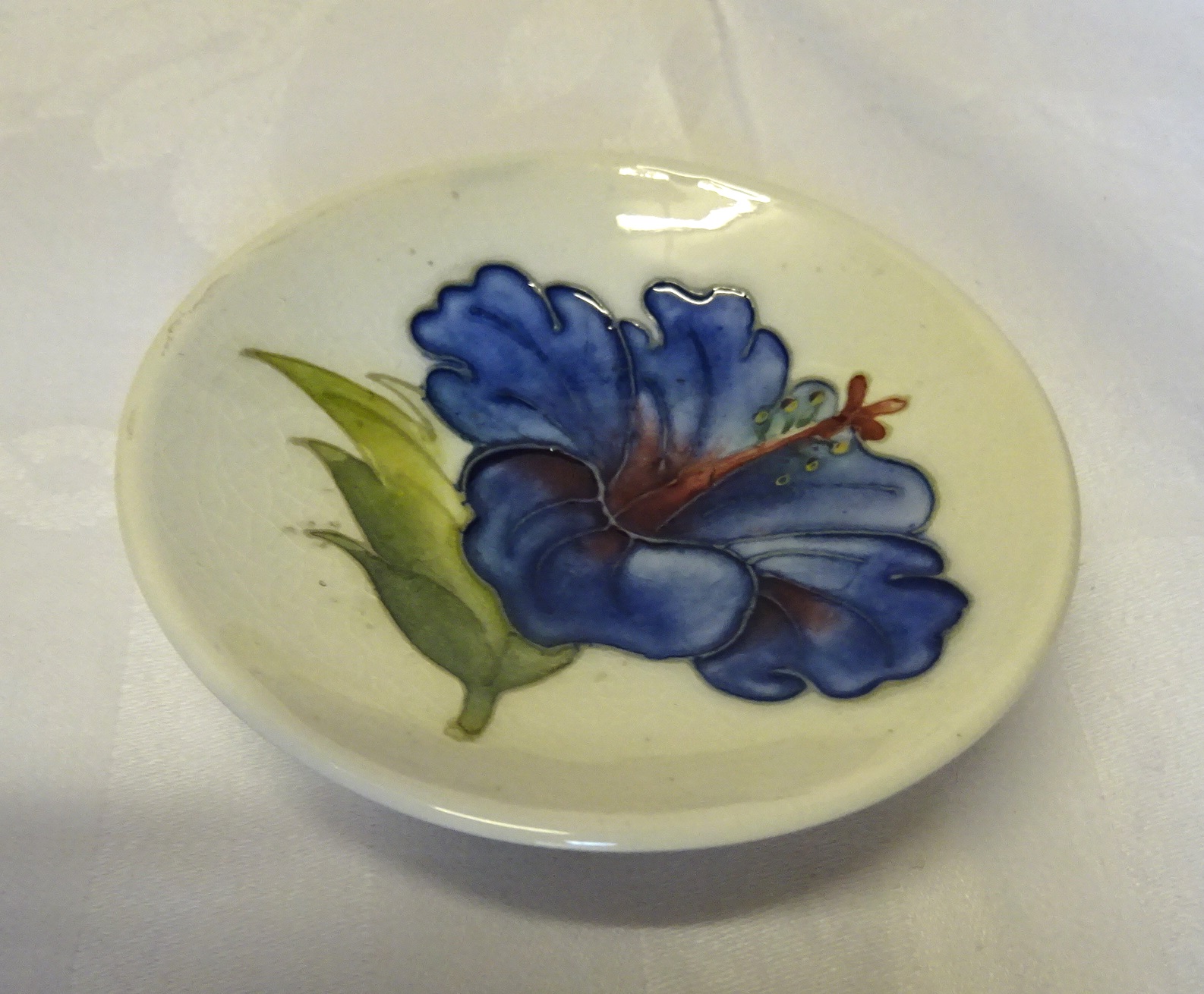 A Moorcroft circular Pin Dish decorated with Hibiscus on a white ground and with paper label to