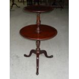 An early 19th Century mahogany two tier circular Dumb Waiter with molded edge on a vase turned