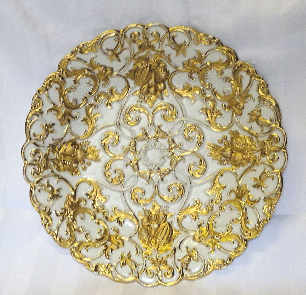 A Meissen circular shallow Dish decorated in gilt with a raised pattern of fruit, leaves, masks