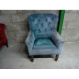 A Victorian tub shape Armchair with buttoned blue upholstery on turned supports.