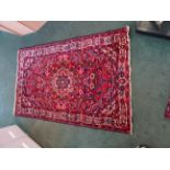 A Central Asian Rug of medallion design decorated with stylised flowers on a red field and bordered,