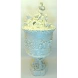 A Belleek Centre Piece in the form of a vase and cover, decorated in relief with cherubs, horses etc