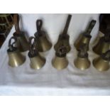 A set of ten brass Handbells with tooled leather strap handles in a pine box.