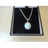 A silver oval Pendant set with an opal and cubic zirconia on a fine link neck chain.