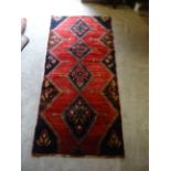 A Hamadan Rug with a centre repeating lozenge design on red field. 7' 8" (234cms) x 3' 7" (110cms).