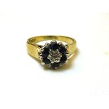 A 9ct. gold Cluster Ring with a small diamond in an illusion setting surrounded by sapphires.