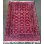 A Turkoman Rug with three rows of octagons on a red field and multi stripe border. 6' (183cms) x