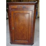 An early 19th Century oak and mahogany banded Corner Wall Cupboard enclosed by a single panel