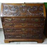 A Georgian oak and pine Bureau with later carved decoration, hinged fall, fitted interior, four long