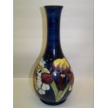 A Moorcroft Baluster Vase decorated with the Orchid pattern on a dark blue ground and with the