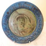 A Fulham Pottery Plate with a painted face, the border inscribed 'Arion', in the style of Quentin