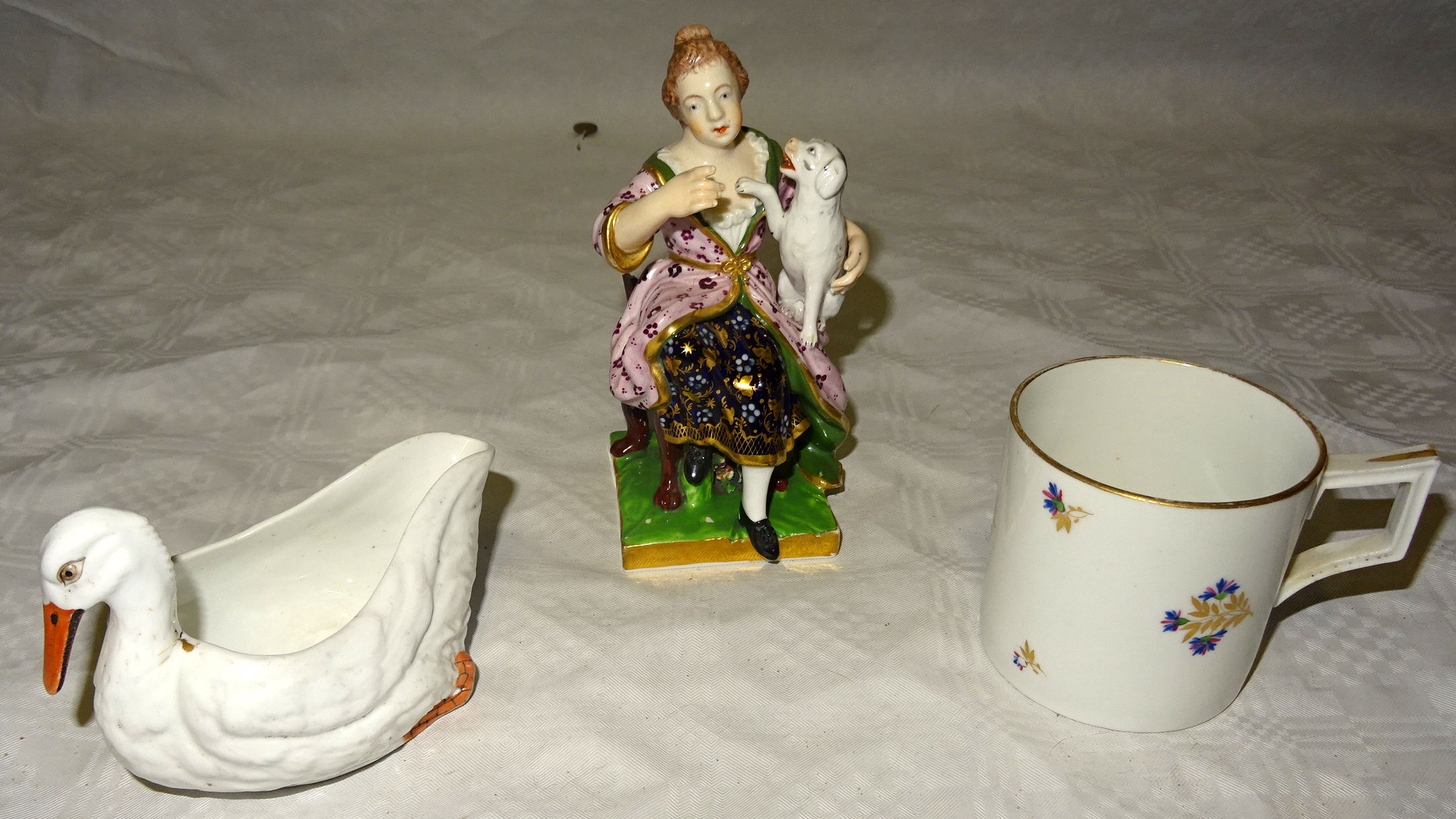 A Bloor Derby figure seated in a chair holding a dog on a square base, 5" (13cms) high (chair