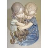 A Royal Copenhagen figure of two children holding a puppy, no. 707. 6" (15cms) high.