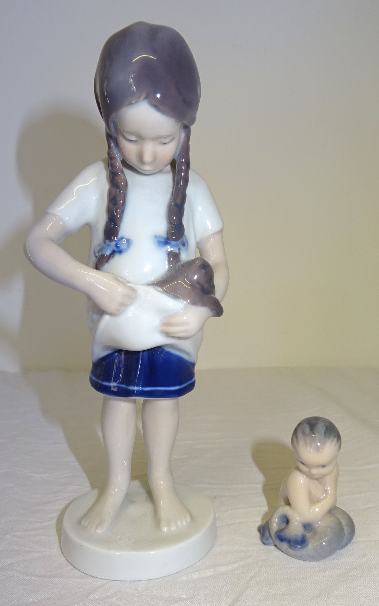 A Royal Copenhagen standing figure of a girl holding a puppy, no. 424. 7" (18cms) high and a small