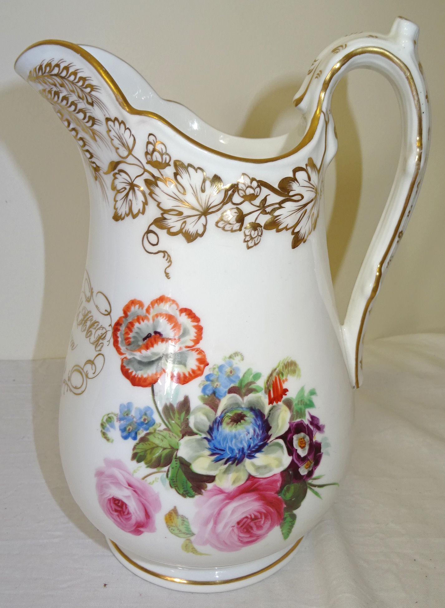 A 19th century Davenport Jug painted with a spray of flowers within a moulded gilt border and