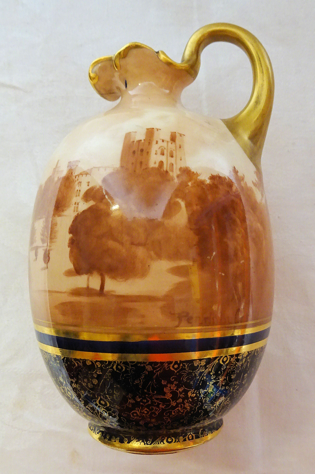 A Doulton Burslem Ewer printed with a scene of Penrhyn Castle with gilt handle, on a blue and gilt